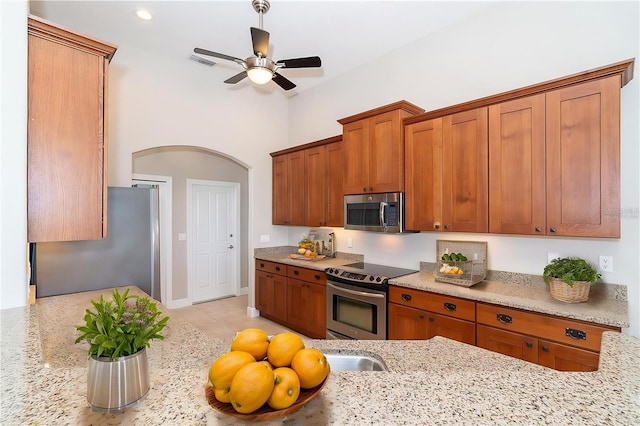 116 Hercules Dr, Rotonda West, FL 33947 - kitchen with appliances with stainless steel finishes, brown cabinets, arched walkways, and ceiling fan