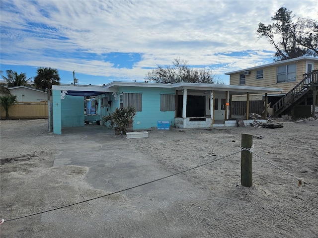 view of front of house with driveway, an attached carport, a porch, and fence