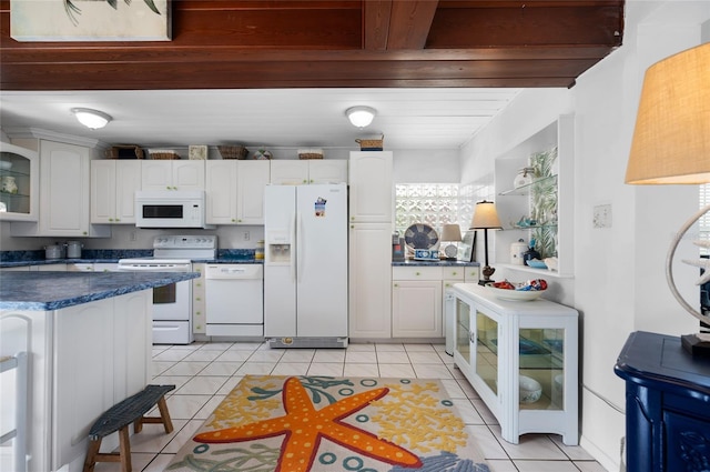 kitchen featuring dark countertops, white appliances, light tile patterned floors, and white cabinets