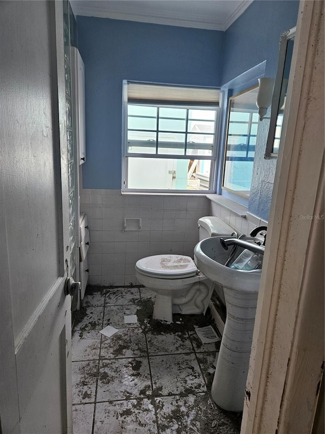 bathroom featuring ornamental molding, a wainscoted wall, tile walls, and toilet