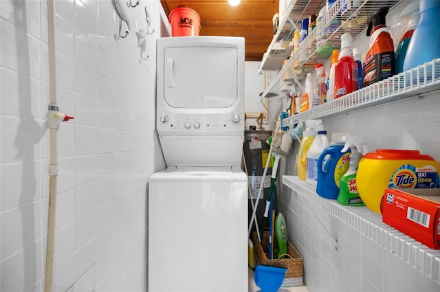 laundry area with laundry area, stacked washer and clothes dryer, and tile walls