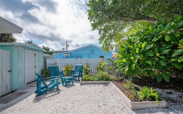 view of patio featuring an outbuilding, a storage shed, a fenced backyard, and a garden