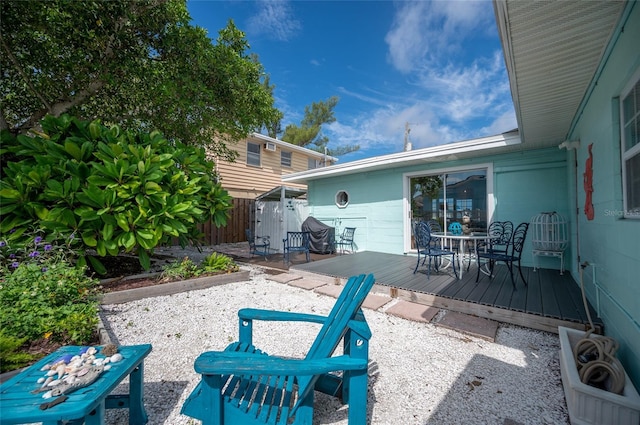 view of patio / terrace with a deck, outdoor dining space, and fence