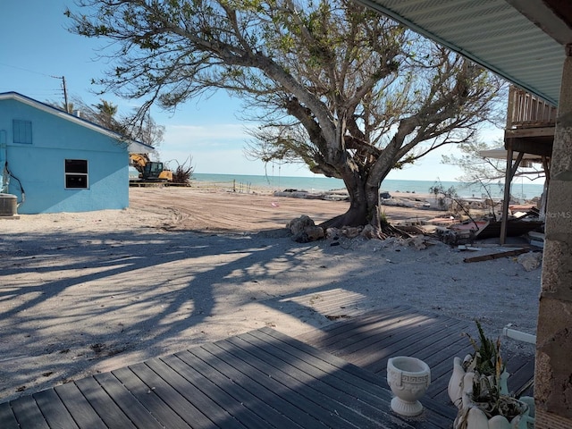 deck with cooling unit, a water view, and a beach view