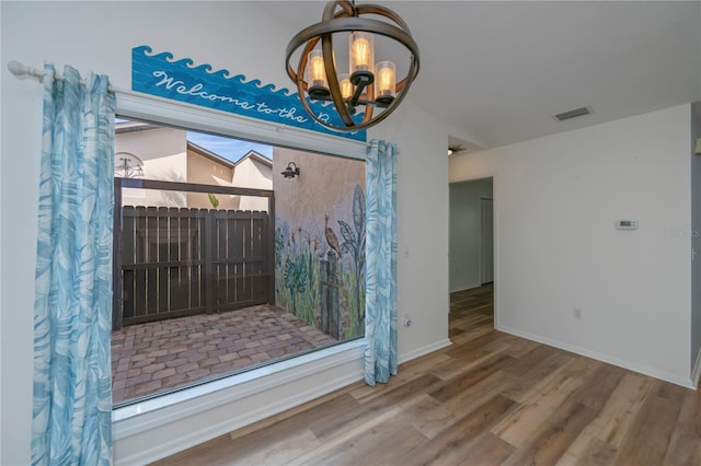 unfurnished dining area featuring an inviting chandelier and wood-type flooring