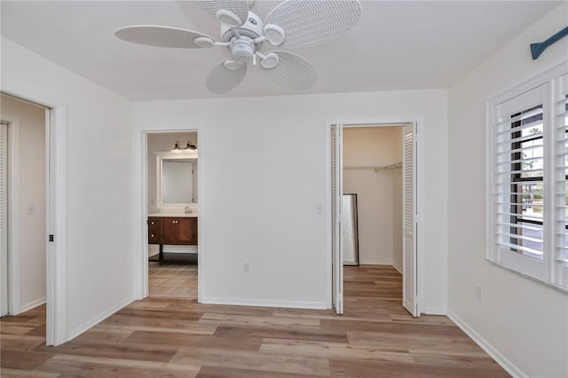 unfurnished bedroom with ceiling fan, ensuite bathroom, light hardwood / wood-style floors, and a closet