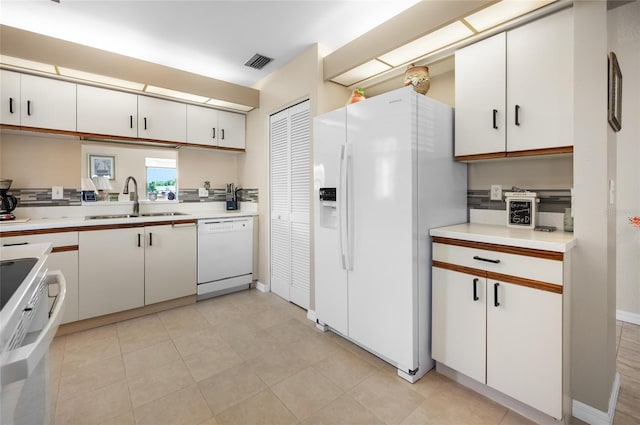 kitchen featuring sink, white appliances, light tile patterned floors, and white cabinets