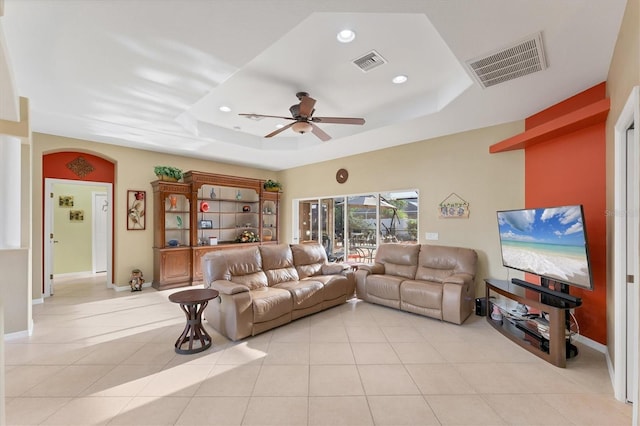 tiled living room with a raised ceiling and ceiling fan