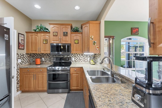 kitchen featuring stainless steel appliances, light tile patterned flooring, light stone countertops, and sink