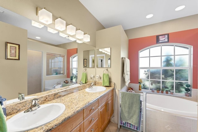 bathroom featuring tile patterned flooring, tiled tub, and vanity