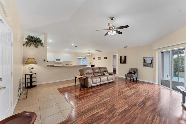 living room featuring light hardwood / wood-style floors, ceiling fan, and vaulted ceiling