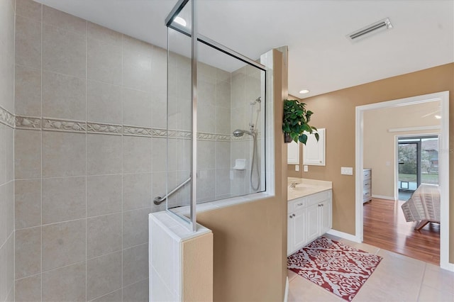 bathroom featuring tile patterned floors, tiled shower, and vanity