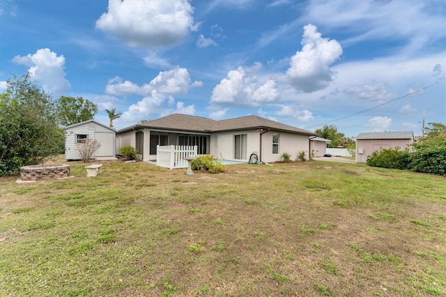 rear view of house with a yard and a storage shed