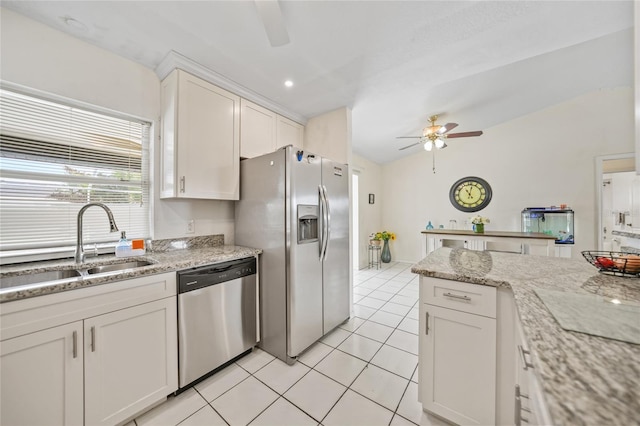 kitchen with stainless steel appliances, sink, white cabinets, light stone counters, and light tile patterned floors