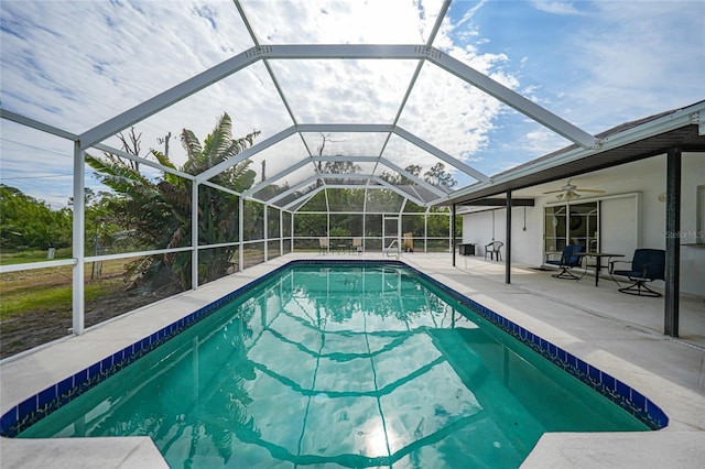 view of swimming pool featuring ceiling fan, glass enclosure, and a patio area