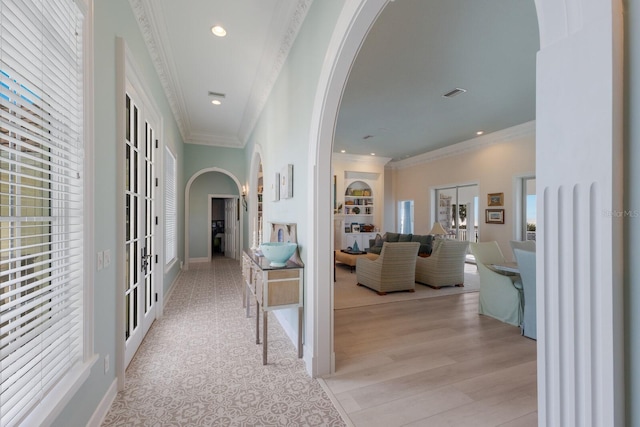 hall with light wood-type flooring, ornamental molding, french doors, and built in shelves