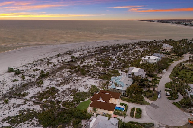 aerial view at dusk with a water view and a beach view