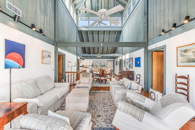 living room featuring ceiling fan, a towering ceiling, and hardwood / wood-style flooring