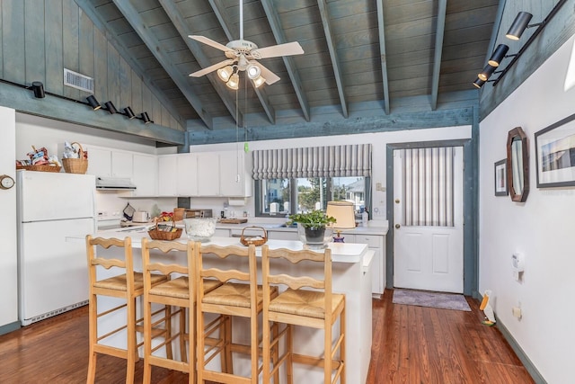 kitchen featuring white appliances, a center island, a kitchen bar, high vaulted ceiling, and beam ceiling