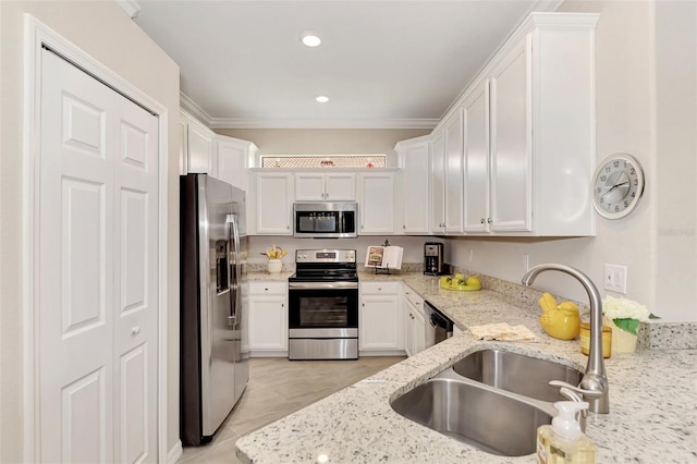 kitchen with light stone counters, stainless steel appliances, white cabinets, ornamental molding, and sink