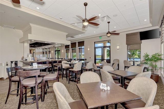 dining space with a raised ceiling, ceiling fan, and crown molding