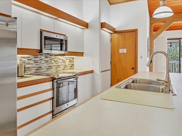 kitchen with tasteful backsplash, sink, white cabinets, hanging light fixtures, and stainless steel appliances