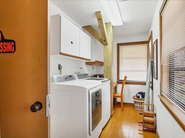 washroom with cabinets, washer and clothes dryer, and light hardwood / wood-style flooring