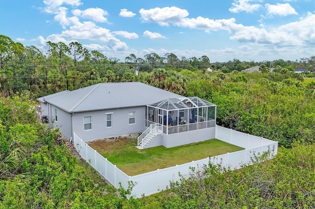 back of property with glass enclosure and a lawn