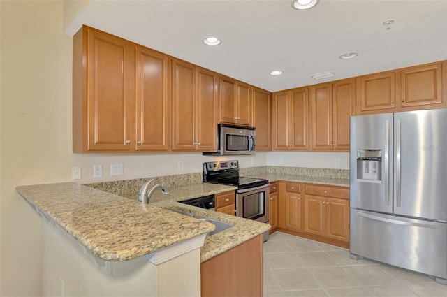 kitchen with appliances with stainless steel finishes, a breakfast bar, sink, kitchen peninsula, and light stone countertops