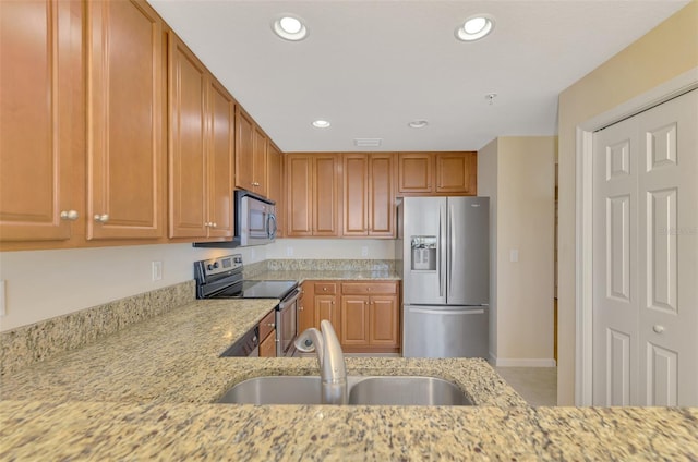 kitchen featuring sink, stainless steel appliances, and light stone countertops