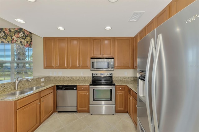 kitchen featuring light stone counters, stainless steel appliances, sink, and light tile patterned floors