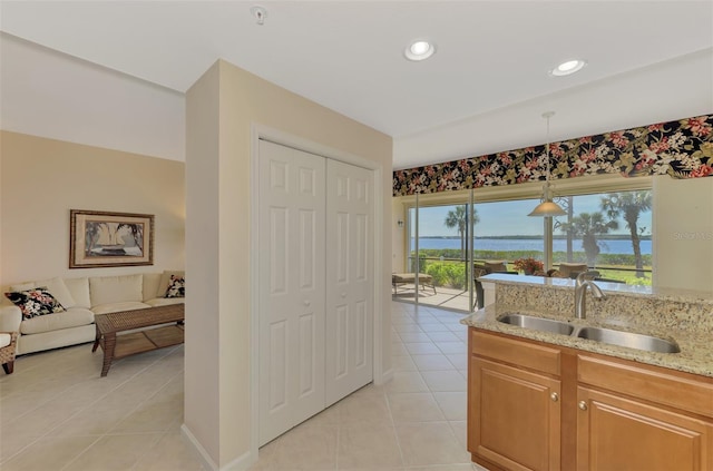 kitchen featuring light stone countertops, sink, light tile patterned floors, and decorative light fixtures