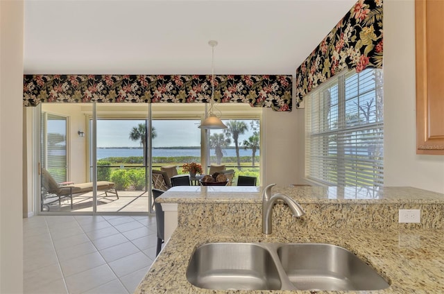 kitchen featuring a wealth of natural light, decorative light fixtures, sink, light tile patterned floors, and light stone countertops