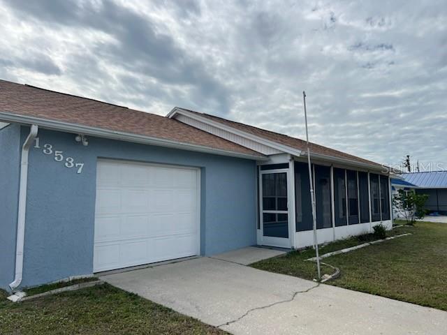 view of front facade with a garage, a front yard, and a sunroom