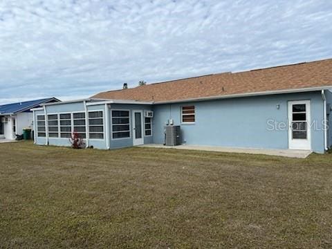 rear view of house featuring central AC and a yard