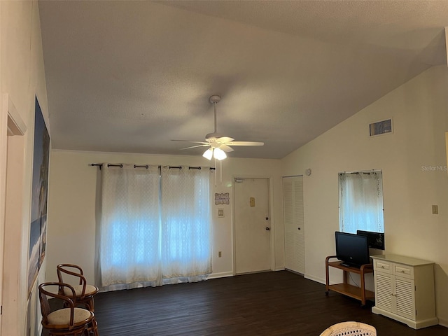 living room featuring dark wood finished floors, lofted ceiling, visible vents, ceiling fan, and baseboards