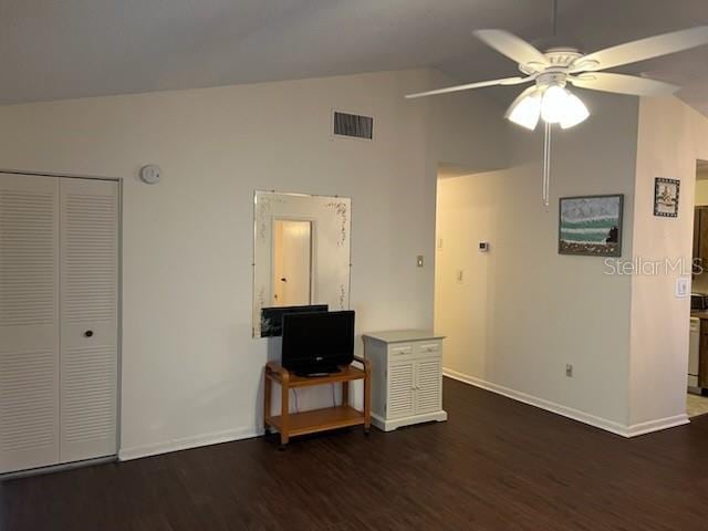 living area with dark wood-type flooring, visible vents, a ceiling fan, vaulted ceiling, and baseboards