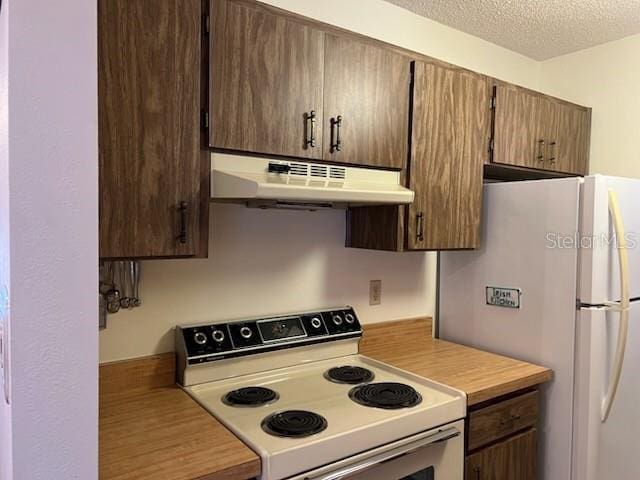 kitchen featuring white appliances, light countertops, under cabinet range hood, and a textured ceiling