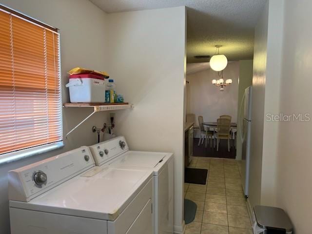 washroom with a textured ceiling, separate washer and dryer, light tile patterned flooring, and a notable chandelier