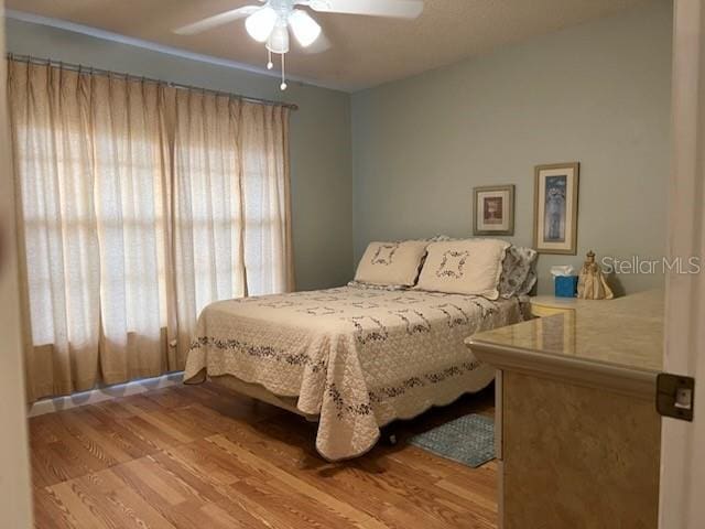 bedroom with ceiling fan, multiple windows, and wood finished floors