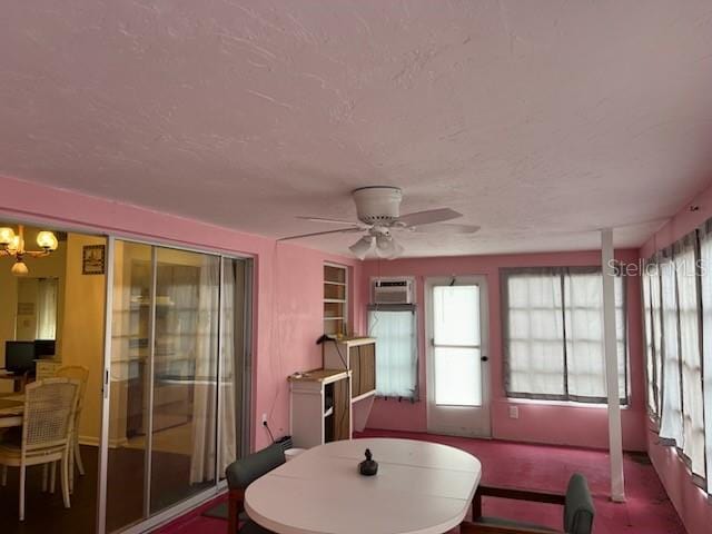 sunroom / solarium with a wall unit AC and ceiling fan with notable chandelier