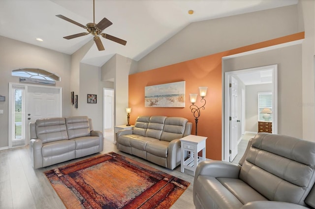 living room with vaulted ceiling, ceiling fan, and light wood-type flooring