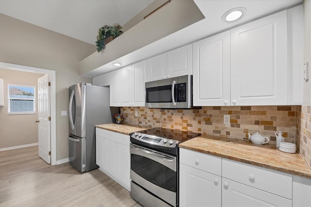 kitchen featuring white cabinetry, appliances with stainless steel finishes, decorative backsplash, light wood-type flooring, and light stone counters