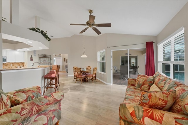 living room featuring ceiling fan, lofted ceiling, and light hardwood / wood-style flooring