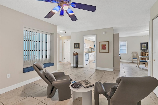 living room with a textured ceiling, ceiling fan, and light tile patterned floors