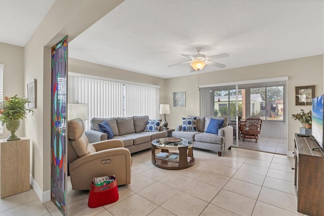 living room with ceiling fan, light tile patterned floors, and a textured ceiling