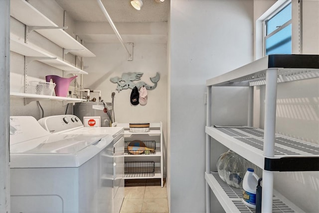 laundry area featuring electric water heater, light tile patterned floors, and washing machine and clothes dryer