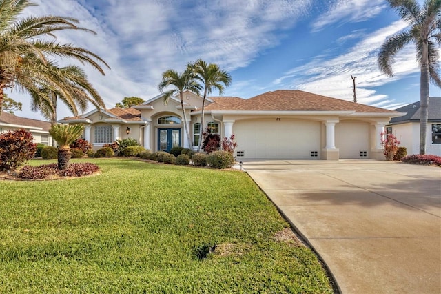 view of front of property featuring french doors, a garage, and a front lawn