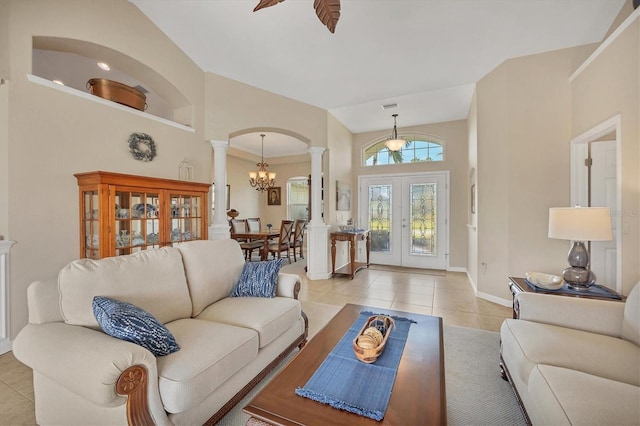 living room featuring ornate columns, ceiling fan with notable chandelier, high vaulted ceiling, light tile patterned floors, and french doors