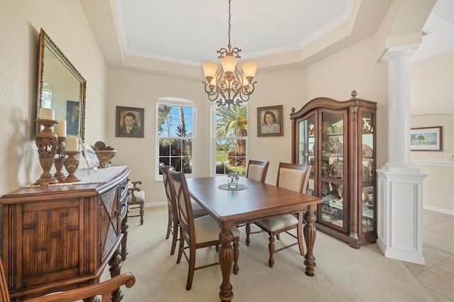 dining space with an inviting chandelier, a tray ceiling, and ornate columns